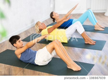 Preteen boy practicing yoga pose lying on back on black rug Preteen boy practicing yoga pose lying on back on black rug 106987839