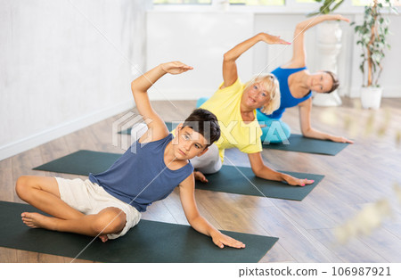 Family is smiling and happily practicing yoga in sports center 106987921