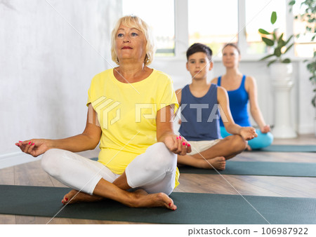 Group of people generation on mats doing yoga exercise lord of fishes pose. 106987922