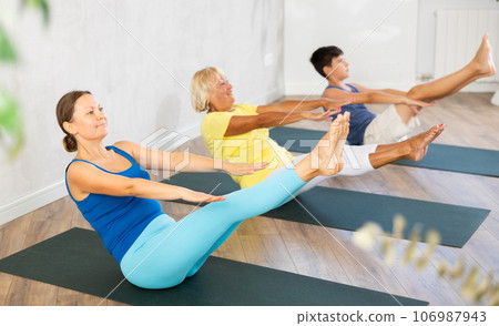 Group of people lying on floor doing yoga exercise boat pose. 106987943