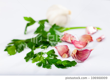 Fresh parsley and garlic over white background Fresh parsley and garlic over white background 106988009