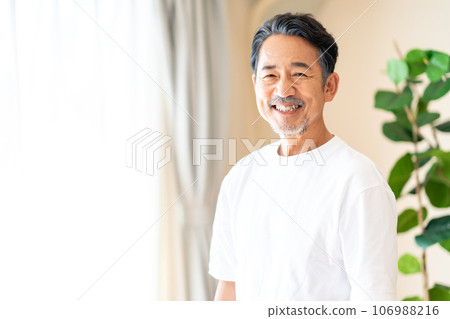 A middle-aged man standing by the window. 106988216