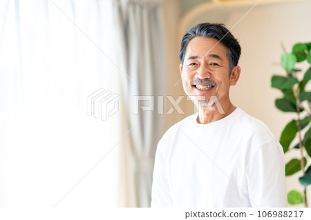 A middle-aged man standing by the window. A middle-aged man standing by the window. 106988217