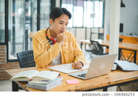 Young Asian college student working and learning on laptop In the cafe. Searching for knowledge online. Young Asian college student working and learning on laptop In the cafe. Searching for knowledge online. 106988253