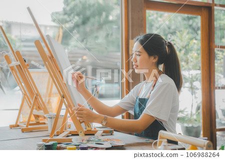 Art student drawing with watercolor painting on canvas doing some art projects on studio workshop Art student drawing with watercolor painting on canvas doing some art projects on studio workshop 106988264