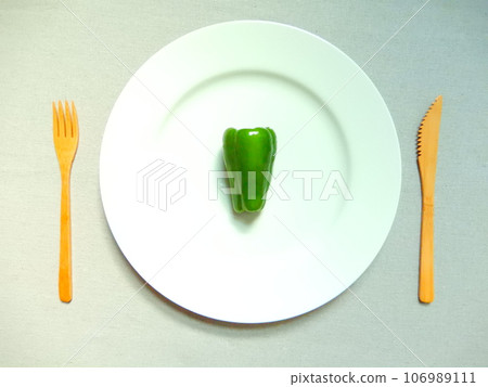 Green peppers and bamboo cutlery on a bright white plate Green peppers and bamboo cutlery on a bright white plate 106989111