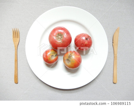 Scratched tomatoes and bamboo cutlery on a white plate Scratched tomatoes and bamboo cutlery on a white plate 106989115