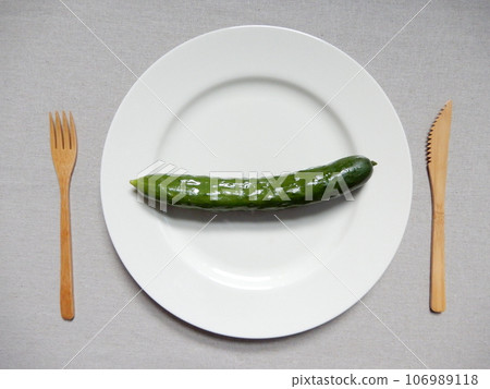 Cucumbers and bamboo cutlery on a white plate 106989118