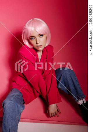 Woman sitting on a pink background, stylish, confident pose. 106989205