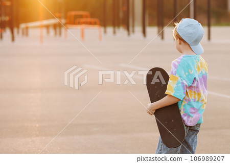 Child girl in casual clothes and jeans stands with skateboard Child girl in casual clothes and jeans stands with skateboard 106989207