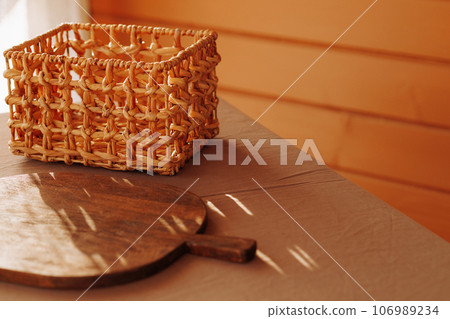 Wooden cutting board and wicker basket close-up 106989234