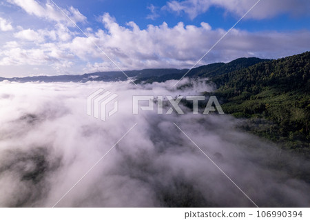 Aerial view of flowing fog waves on mountain tropical rainforest,Bird eye view image over the clouds Amazing nature background with clouds and mountain peaks in Thailand Aerial view of flowing fog waves on mountain tropical rainforest,Bird eye view image over the clouds Amazing nature background with clouds and mountain peaks in Thailand 106990394