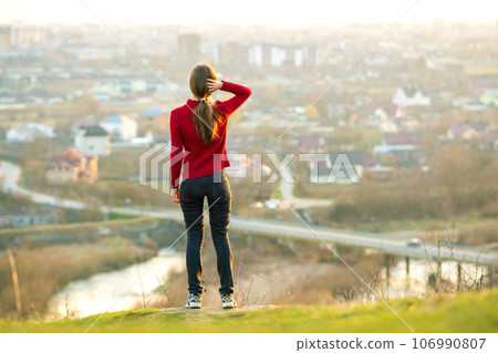 Young woman standing outdoors enjoying city view. Relaxing, freedom and wellness concept. 106990807