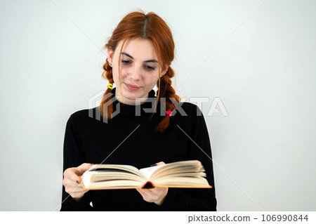 Young pretty girl read an open book in her hands. Reading and education concept. Young pretty girl read an open book in her hands. Reading and education concept. 106990844