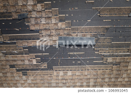 Wind damaged house roof with missing asphalt shingles after hurricane Ian in Florida. Repair of home rooftop concept Wind damaged house roof with missing asphalt shingles after hurricane Ian in Florida. Repair of home rooftop concept 106991045