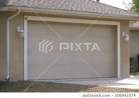Wide garage double door and concrete driveway of new modern american house Wide garage double door and concrete driveway of new modern american house 106991074