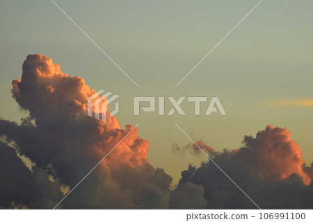 White fluffy cumulonimbus clouds forming before thunderstorm on evening sky. Changing stormy cloudscape weather at sunset 106991100