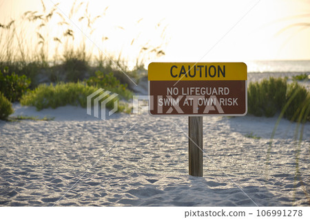 Warning sign poster on sea side beach saying that there is no lifeguard on duty 106991278