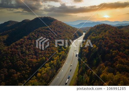 View from above of I-40 freeway in North Carolina heading to Asheville through Appalachian mountains in golden fall season with fast driving trucks and cars. Interstate transportation concept 106991285