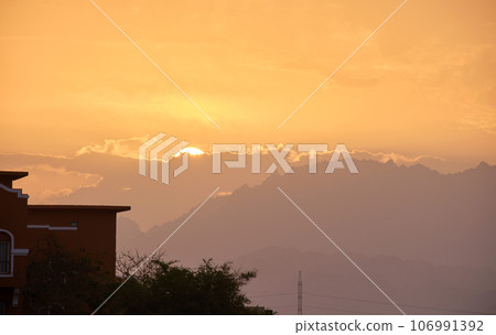 Sunset landscape with remote hotel complex against dark mountain peaks in egyptian desert 106991392