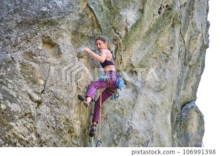 Strong female climber climbing steep wall of rocky mountain. Sportswoman overcoming difficult route. Engaging in extreme sports hobby concept. Strong female climber climbing steep wall of rocky mountain. Sportswoman overcoming difficult route. Engaging in extreme sports hobby concept. 106991398