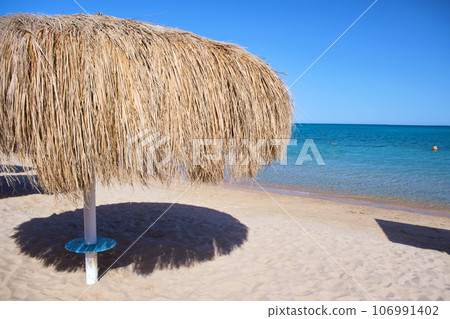 Straw shade umbrella in sea tropical region against blue vibrant sky in summer 106991402