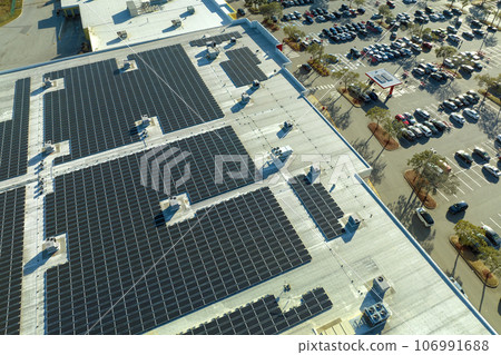 Production of sustainable energy. Solar power plant with blue photovoltaic panels mounted on commercial shopping store building roof for producing green ecological electricity 106991688