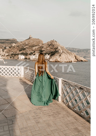 Woman sea green dress. Side view a happy woman with long hair in a long mint dress posing on a beach with calm sea bokeh lights on sunny day. Girl on the nature on blue sky background. 106992014