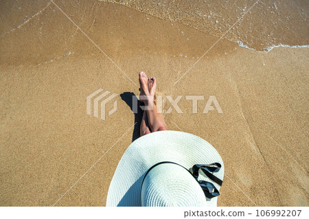Long slim young woman legs relaxing lying down and sunbathing on sand tropical beach under hot sun in summer. Skincare, sun aging protection and sea travel concept. 106992207