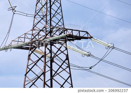 High voltage tower with electric power lines divided by safe guard bushing transfening safely electrical energy through cable wires. Electricity transmission on long distance concept 106992237