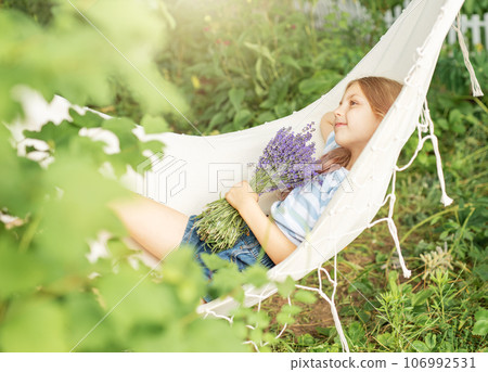 A little girl rests in a hammock in the summer. A little girl rests in a hammock in the summer. 106992531