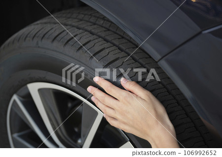 Female driver hands inspecting wheel tire of her new car. Vehicle safety concept 106992652