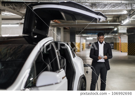 Adult in business suit thumbing through cash in EV parking Adult in business suit thumbing through cash in EV parking 106992698
