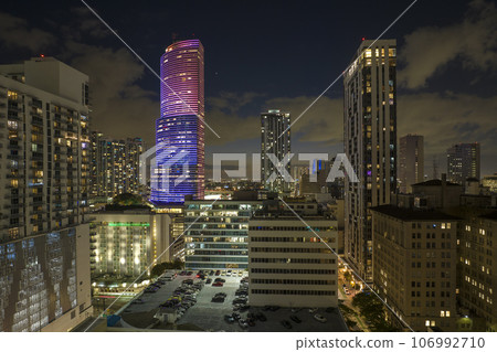 Downtown district of of Miami Brickell in Florida, USA. Brightly illuminated high skyscraper buildings and street with cars and Metrorail traffic in modern american midtown Downtown district of of Miami Brickell in Florida, USA. Brightly illuminated high skyscraper buildings and street with cars and Metrorail traffic in modern american midtown 106992710