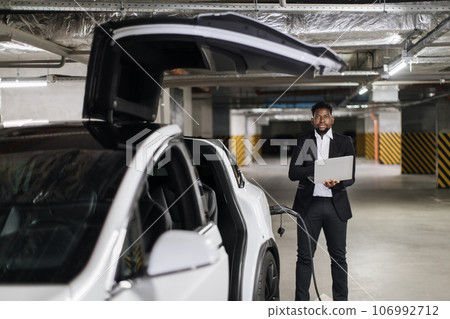 Employee with laptop working in EV underground garage 106992712