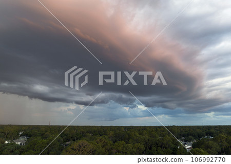 Dark stormy clouds forming on gloomy sky before heavy rainfall over suburban town area Dark stormy clouds forming on gloomy sky before heavy rainfall over suburban town area 106992770
