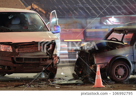 Damaged in heavy car accident vehicles after collision on city street crash site at night. Road safety and insurance concept 106992795