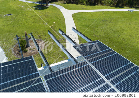 Damaged by hurricane wind photovoltaic solar panels mounted on parking lot canopy roof for producing green ecological electricity. Consequences of natural disaster in Florida, USA 106992801