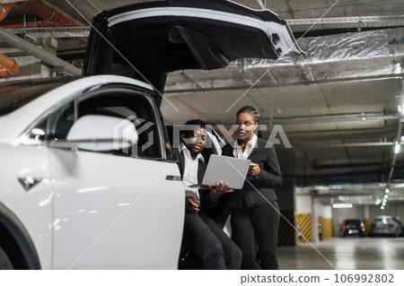 Work partners watching video on laptop in e-car in parking 106992802
