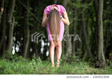 Creepy woman with long hair leaning bent down in moody dark forest. Creepy woman with long hair leaning bent down in moody dark forest. 106992806