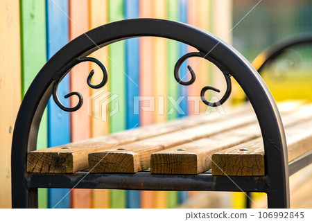 Closeup of wooden park bench with metal handgrip outdoors. 106992845