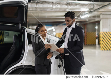 Male putting e-signature via tablet during e-car fill-up 106992896