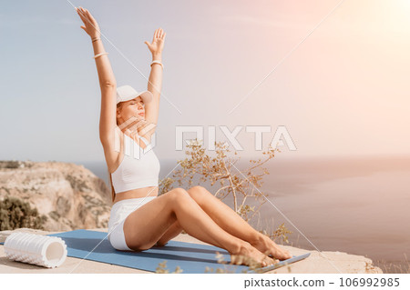 Fitness woman sea. Outdoor workout on yoga mat roller in park near to ocean beach. Female fitness pilates yoga routine concept. Healthy lifestyle. Happy fit woman exercising with rubber band in park. Fitness woman sea. Outdoor workout on yoga mat roller in park near to ocean beach. Female fitness pilates yoga routine concept. Healthy lifestyle. Happy fit woman exercising with rubber band in park. 106992985