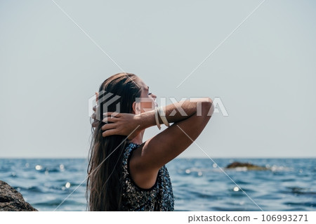 Woman summer travel sea. Happy tourist enjoy taking picture outdoors for memories. Woman traveler posing on the beach at sea surrounded by volcanic mountains, sharing travel adventure journey Woman summer travel sea. Happy tourist enjoy taking picture outdoors for memories. Woman traveler posing on the beach at sea surrounded by volcanic mountains, sharing travel adventure journey 106993271
