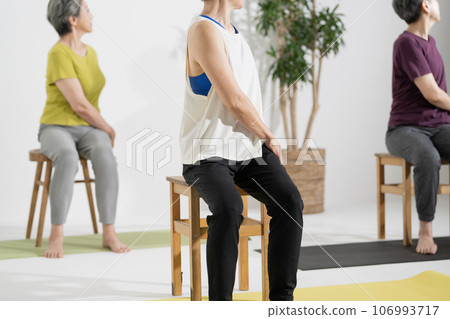 Senior yoga/woman in her 60s doing chair yoga Senior yoga/woman in her 60s doing chair yoga 106993717