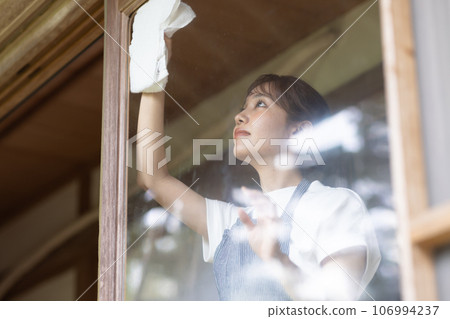 一位年輕女子正在擦一棟古老民居的窗戶 106994237