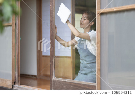 一位年輕女子正在擦一棟古老民居的窗戶 106994311