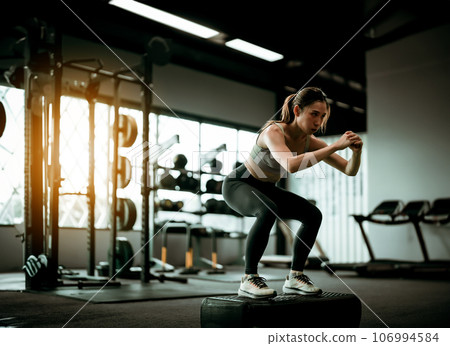 Young Sportive Woman Workout Exercising with Jumping Step Platform at Fitness Center 106994584