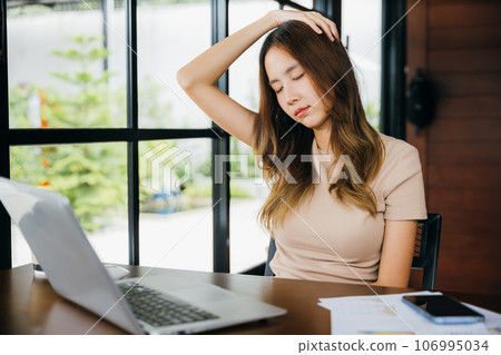 Tired office woman sitting at desk touching massaging stiff neck while holding her head in cafe, Asian business woman suffering from neck ache pain caused by sitting working long time laptop usage 106995034