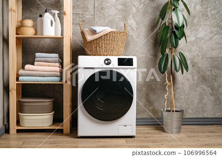 Laundry room interior with washing machine near gray grunge wall Laundry room interior with washing machine near gray grunge wall 106996564